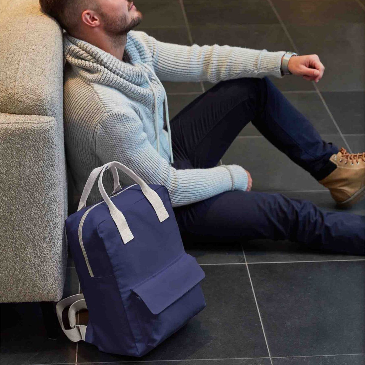 Blauer Rucksack auf dem Boden neben Mann