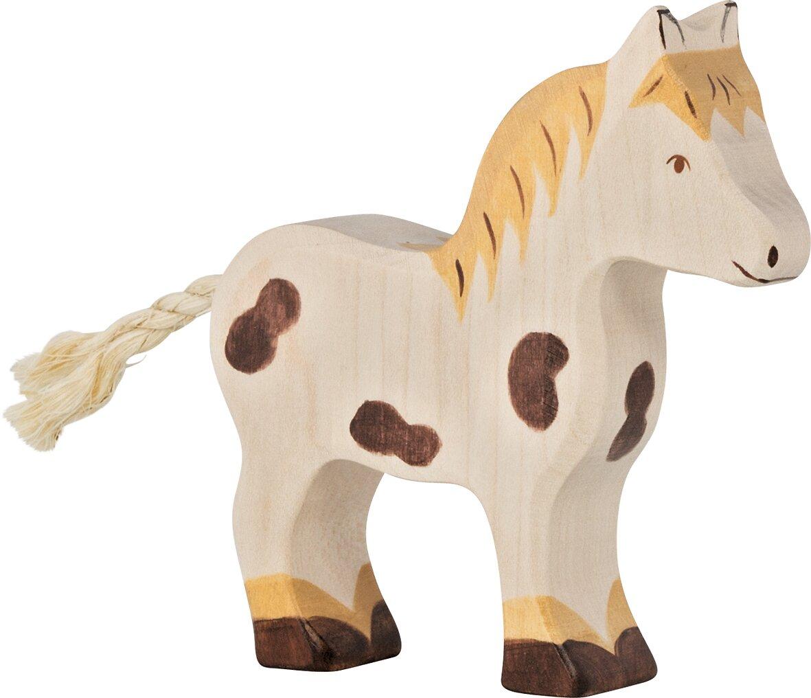 Holzpony mit Zopfschweif und braunen Flecken